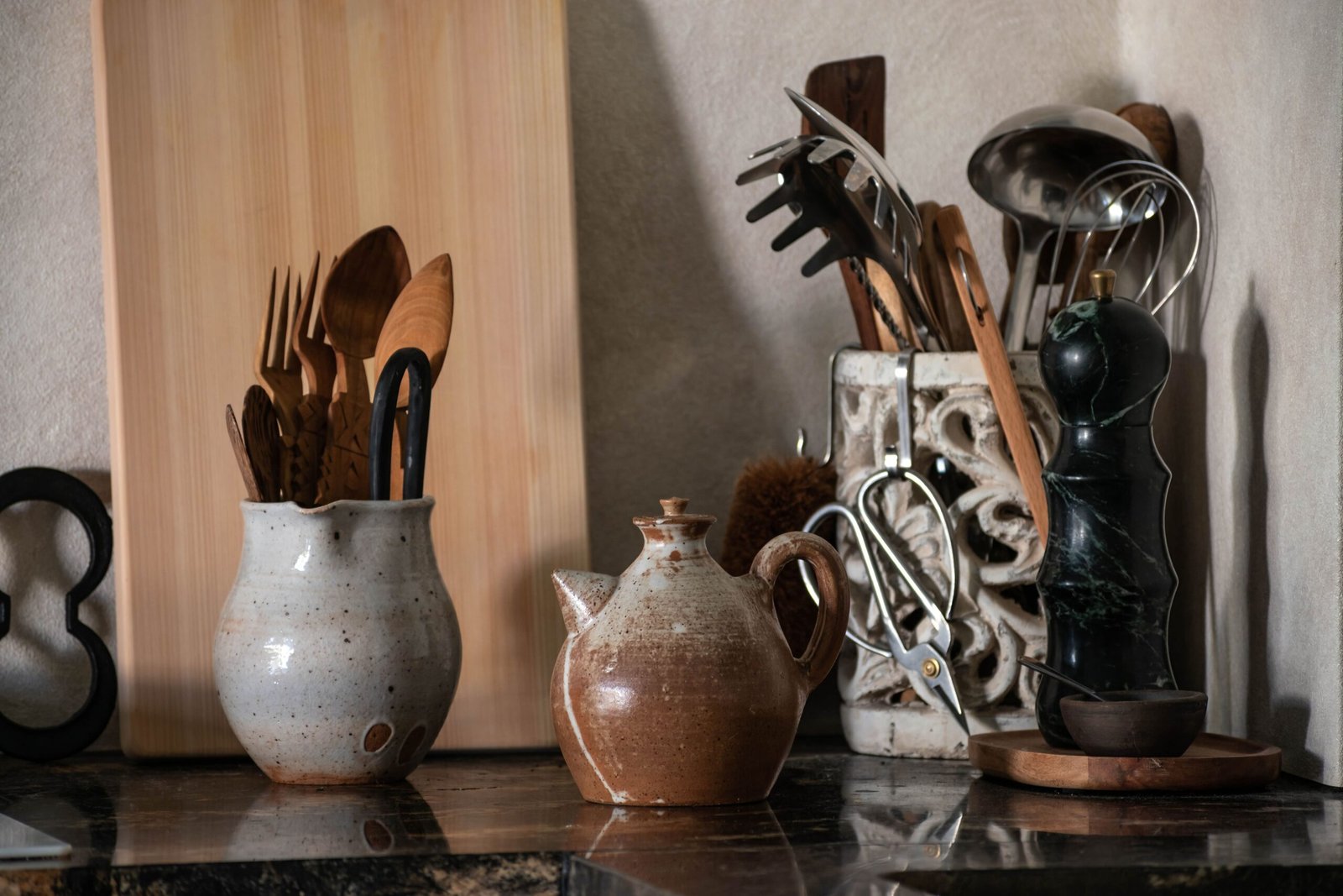 Rustic kitchen setup with wooden utensils, a cutting board, kitchen tools, and ceramic cookware.